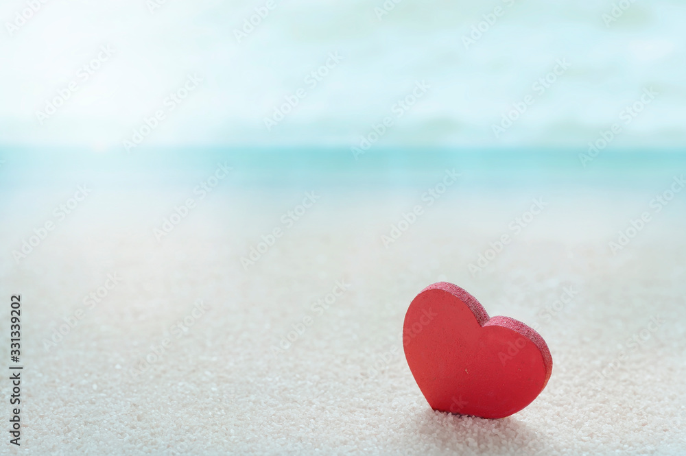 Red wooden heart model on the sandy sea beach with blue sea blurred background. Red wooden heart model on the sandy sea beach with blue sea blurred background.