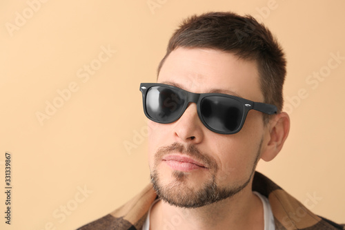 Handsome man with sunglasses on color background