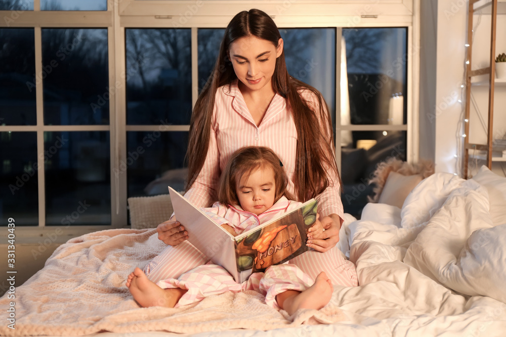 Obraz premium Mother and her little daughter reading bedtime story at home