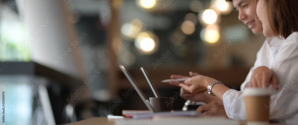 Side view of two businesspeople brainstorming on their work with laptop computer