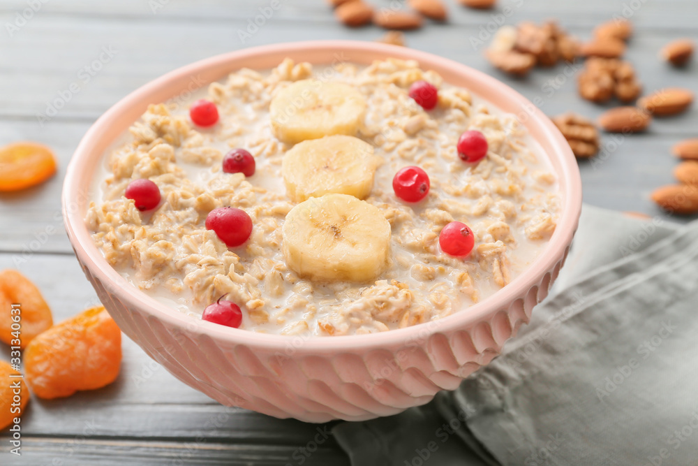 Bowl with tasty sweet oatmeal on table - obrazy, fototapety, plakaty 