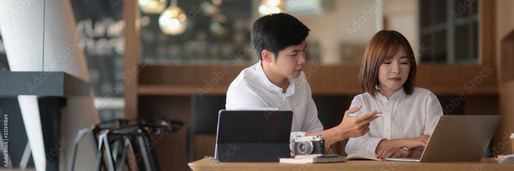 Cropped shot of two photographer sitting in co-working space and consulting on their project Cropped shot of two photographer sitting in co-working space and consulting on their project