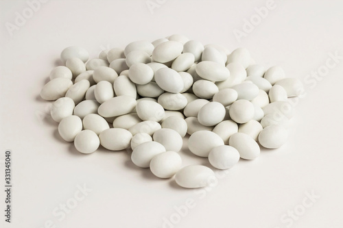 Traditional Turkish chocolate coated almonds (badem sekeri) on the white surface.Close up taken of heap almonds.