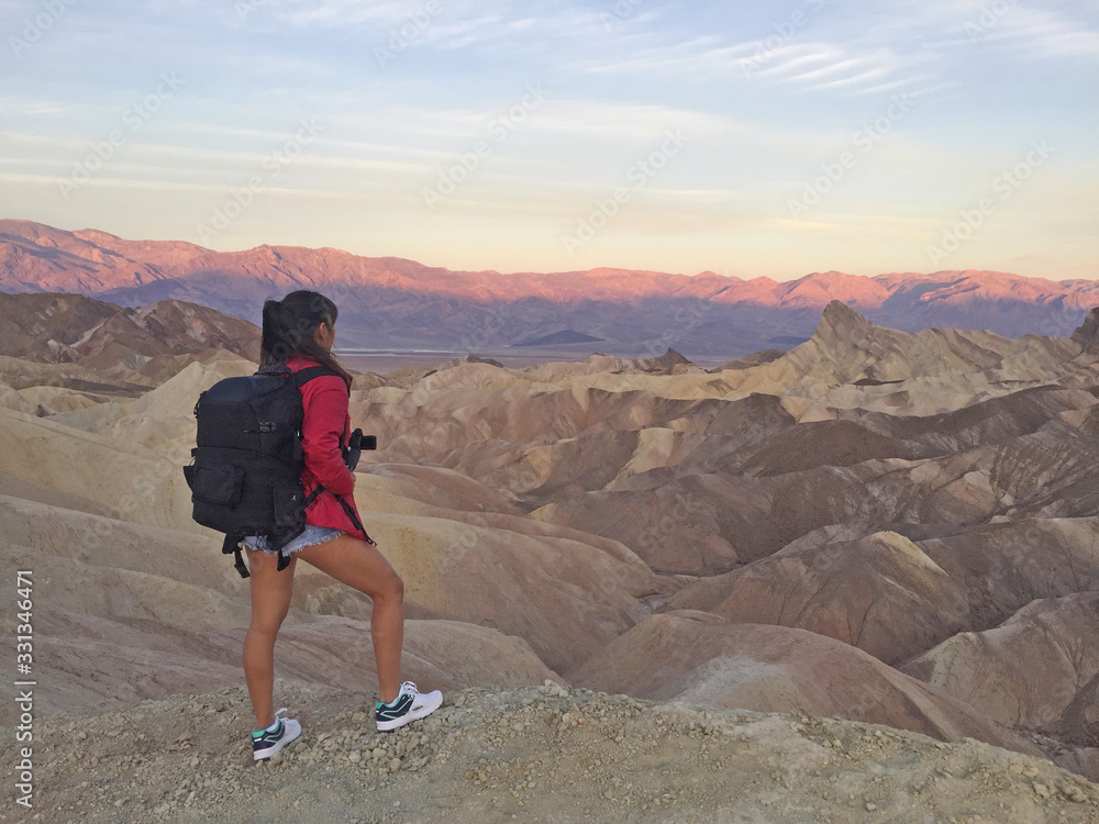Fototapeta premium Woman watching beautiful sunrise from Zabriskie Point at Death Valley National Park in California USA