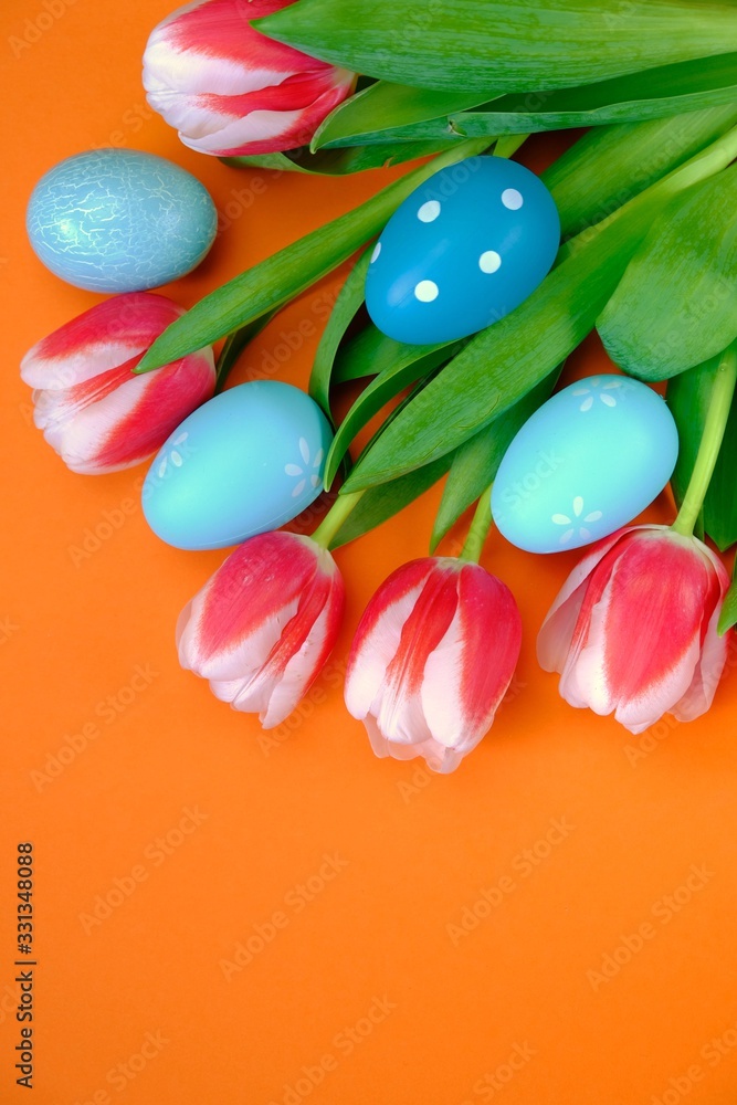 Easter holiday. Decorative easter eggs in tulip flowers on a bright orange background.Spring holiday background Easter holiday. Decorative easter eggs in tulip flowers on a bright orange background.Spring holiday background
