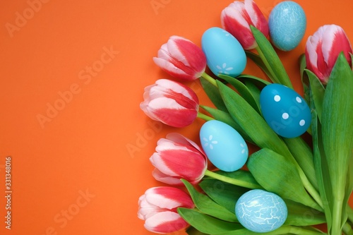 Easter holiday. Decorative blue easter eggs in tulip flowers on a  orange background.Spring holiday background