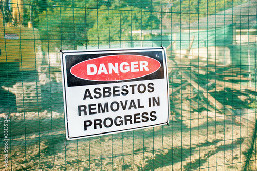 Valokuva A warning sign Danger Asbestos on a fence at construction site where old house i