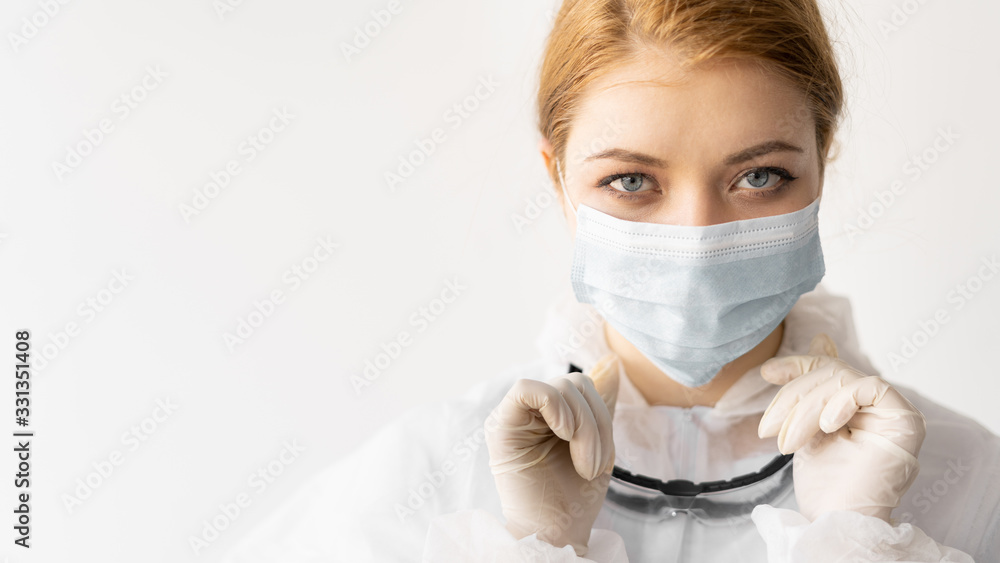 young woman in a white coat on a white background. Medical face mask safety glasses