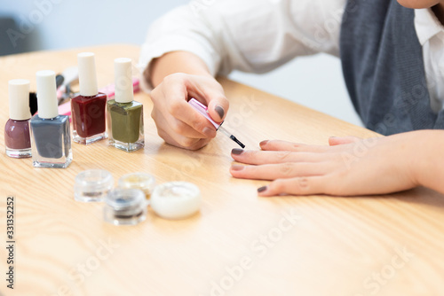A young woman paints her own nail polish at home