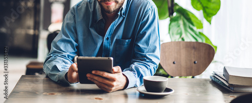 Handsome hipster man relaxing using digital tablet computer and looking at screen relaxing with device work study while sitting on chair in cafe and restaurant.technology and communication concept