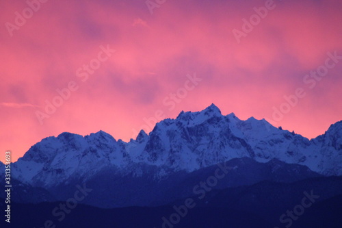 Snow capped mountains in front of a pink sunset sky
