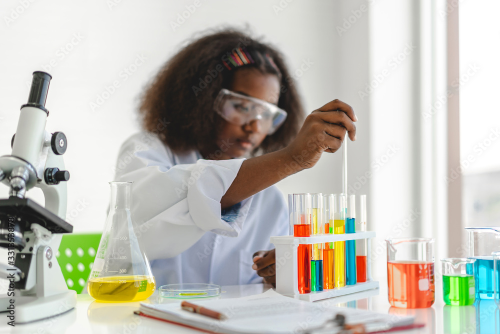 African american cute little girl student child learning research and doing a chemical experiment while making analyzing and mixing liquid in glass at science class on the table.Education and science African american cute little girl student child learning research and doing a chemical experiment while making analyzing and mixing liquid in glass at science class on the table.Education and science