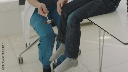 Doctor Testing Boy'S Reflexes With Reflex Hammer On Knee