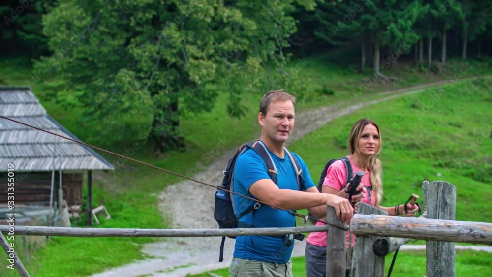 An active couple opening a fence and leaving their wooden hut accommodation to hike in the woods An active couple opening a fence and leaving their wooden hut accommodation to hike in the woods