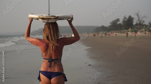 Young attractive surfer girl in bikin on the beach with surf