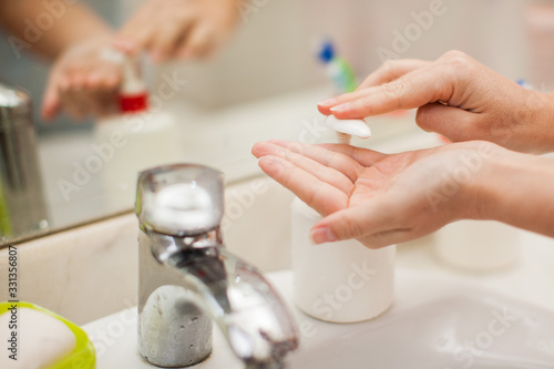 Woman antibacterial liquid soap for hands in bathroom. People and healthcare concept.