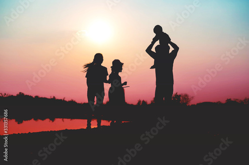 Silhouette of a family comprising a father  mother and two children happy family the sunset.Concept of friendly 