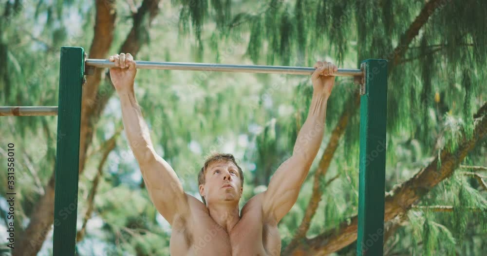 Fit muscular man working out doing pull ups outdoors, health and fitness routine Fit muscular man working out doing pull ups outdoors, health and fitness routine