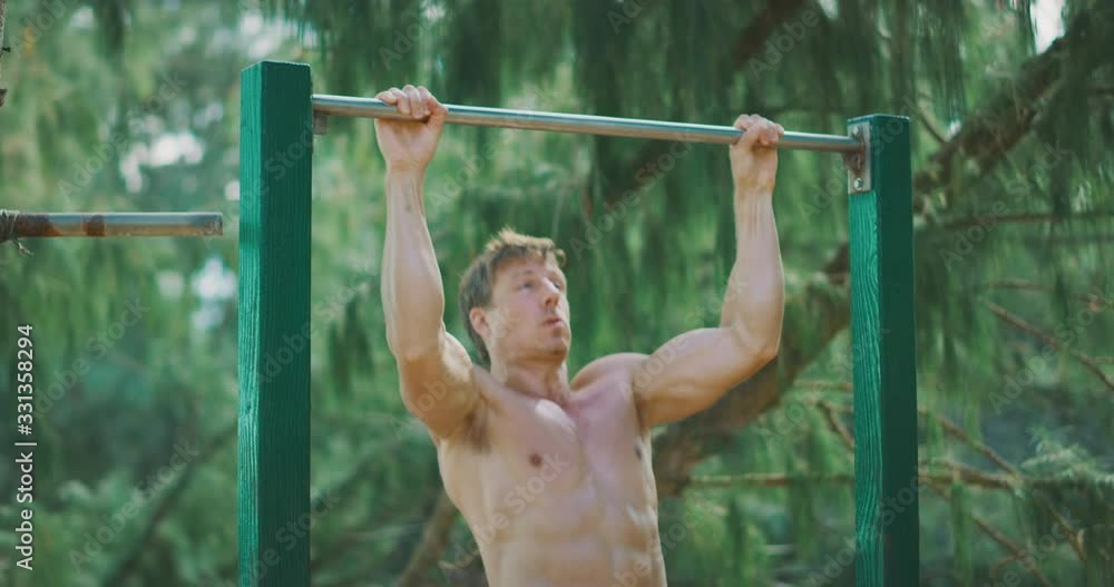 Fit muscular man working out doing pull ups outdoors, health and fitness routine Fit muscular man working out doing pull ups outdoors, health and fitness routine