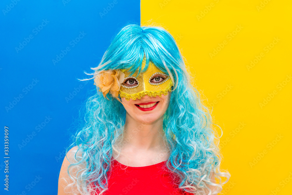 Beautiful white woman dressed for a Carnival night. A smiling girl in a blue wig and yellow mask is going to celebrate a masquerade. Animator for children's birthday entertainment