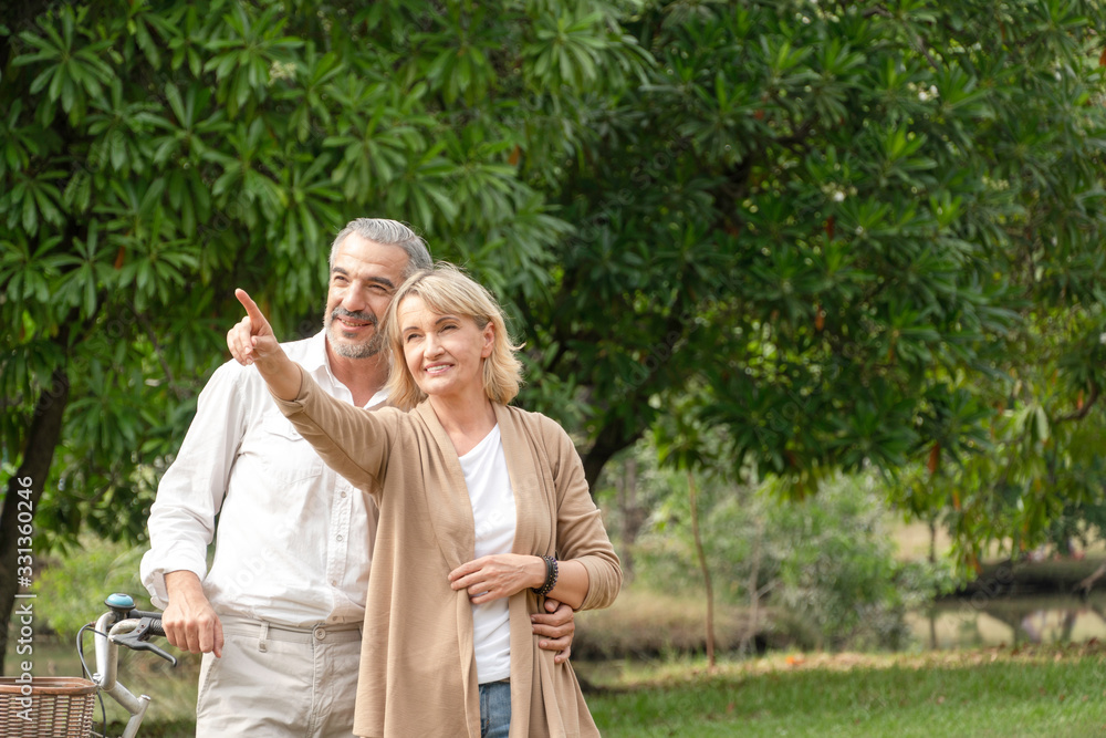 portrait happy romance senior couple embrace together, old woman pointing hand to sky and talk about future with a man, husband wrap around his wife's waist, retirement lifestyle at park for insurance portrait happy romance senior couple embrace together, old woman pointing hand to sky and talk about future with a man, husband wrap around his wife's waist, retirement lifestyle at park for insurance