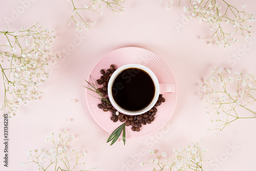 Flat lay with a Cup of black morning coffee surrounded by spring flowers in pastel monochrome tones