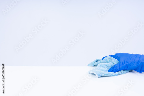 A hand with blue nitirl gloves cleaning a white surface