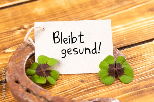 horseshoe with green shamrock and german text bleibt gesund, in english stay healthy photo