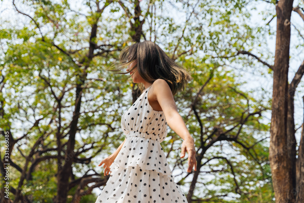Happy and carefree young 20s woman dancing in the outdoor forest with green trees. Portrait of beautiful girl relaxing. Freedom and happiness concept Happy and carefree young 20s woman dancing in the outdoor forest with green trees. Portrait of beautiful girl relaxing. Freedom and happiness concept