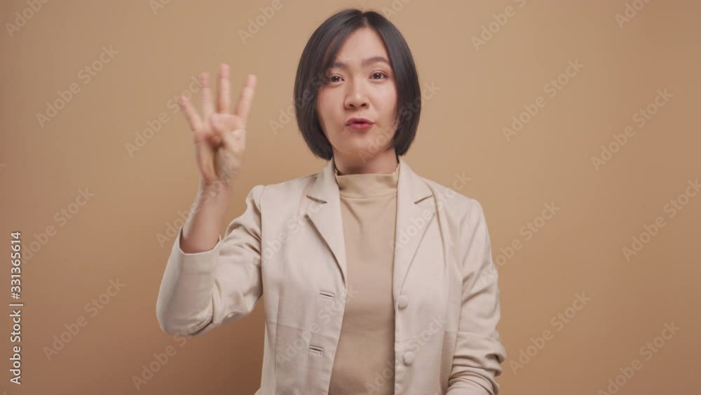 Asian business woman show counting numbers with fingers and smiling isolated over beige background. 4K video Asian business woman show counting numbers with fingers and smiling isolated over beige background. 4K video