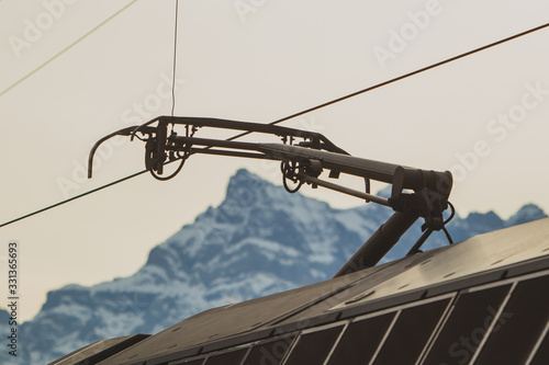 Pantoghraph, the device to pick up current from overhead lines on swiss railways. Visible mountains in switzerland in the background.