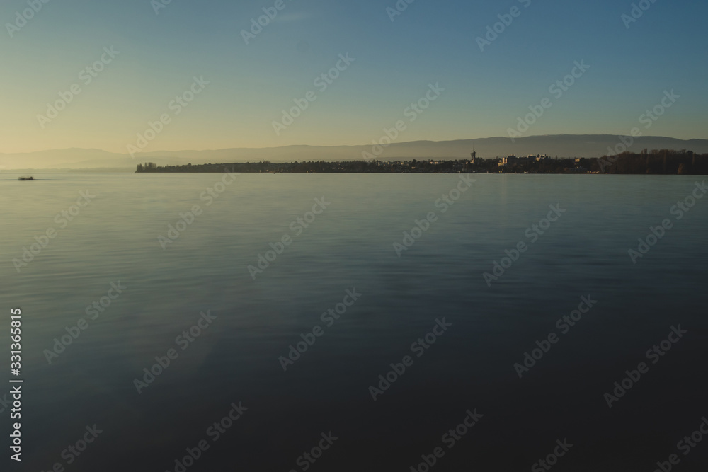 Beautiful evening photo of Lac Leman close to Lausanne, with sun just above the horizon and long exposure of water.
