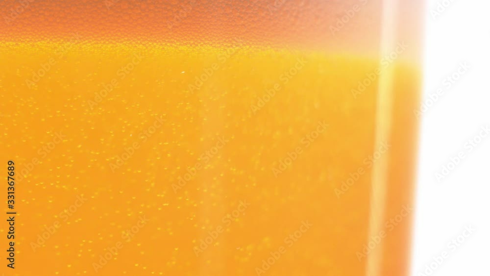 Macro shot of bubbles rising in a glass with orange liquid, beer in slow motion. Macro shot of bubbles rising in a glass with orange liquid, beer in slow motion.