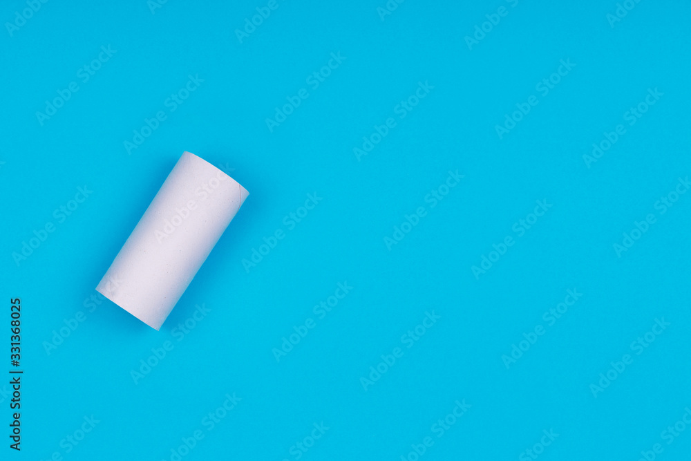 Toilet paper empty sleeve on the bright blue background. Coronavirus pandemic panic shopping concept. Bright monochrome drop