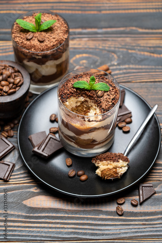 Classic tiramisu dessert in a glass cup on wooden background