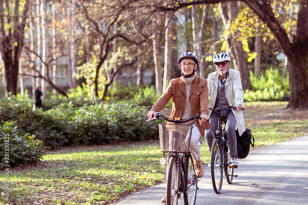 Senior couple with bycicles and helmets in park