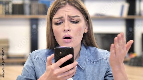 Creative Woman Reacting to Loss while Using Smartphone