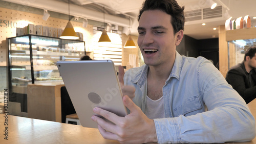 Video Chat on Tablet by Young Man in Cafe photo