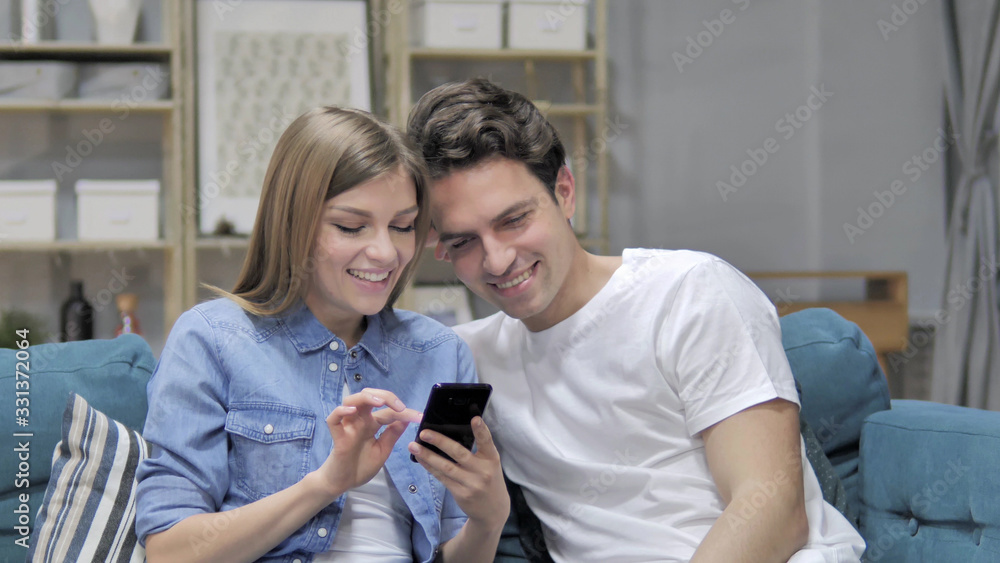 Happy Young Couple Browsing Internet on Smartphone at Home Happy Young Couple Browsing Internet on Smartphone at Home