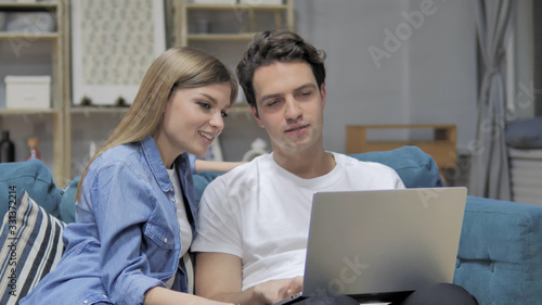 Young Couple Discussing Online on Laptop at Home © stockbakers