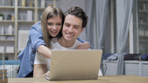 Casual Happy Young Couple Using Laptop at Home
