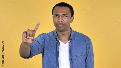 Young African Man Waving Finger to Refuse Isolated on Yellow Background