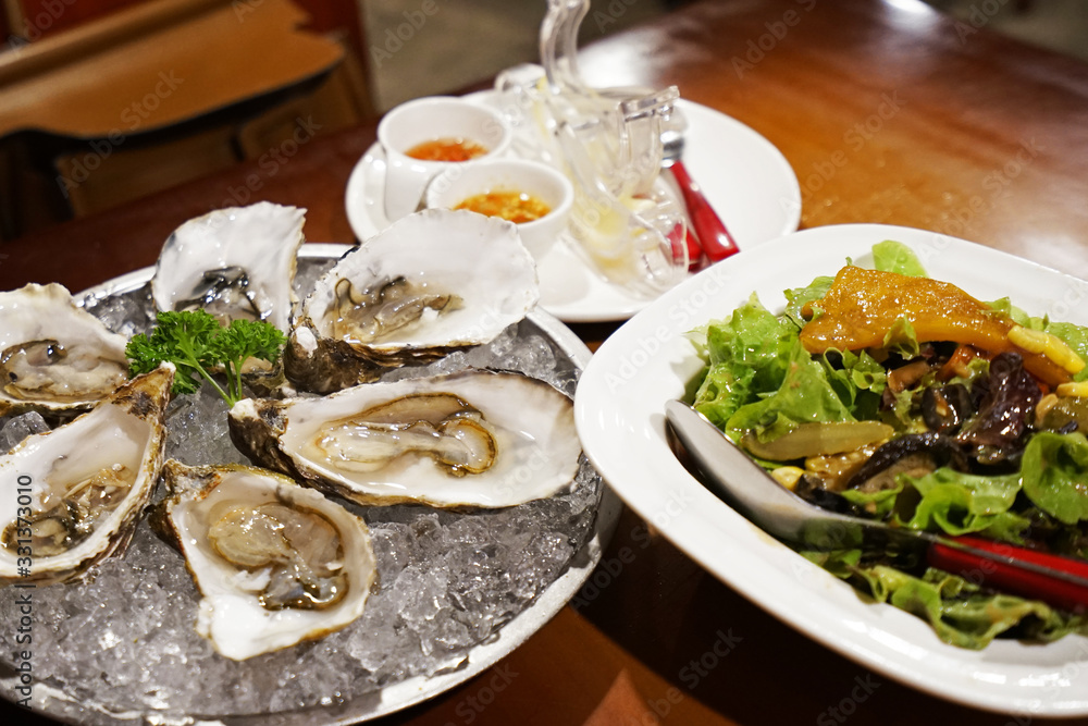 Close up Fresh oysters on crushed ice cube with Salmon salad