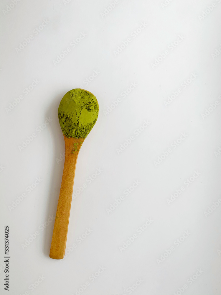 wooden spoon with powdered matcha green tea in bowl, isolated on white background wooden spoon with powdered matcha green tea in bowl, isolated on white background