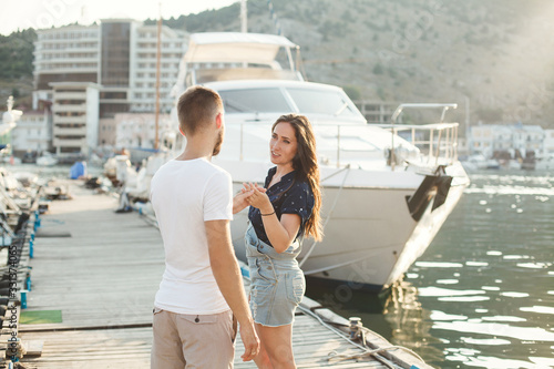 Lovers walk on the pier against the backdrop of yachts and boats.
