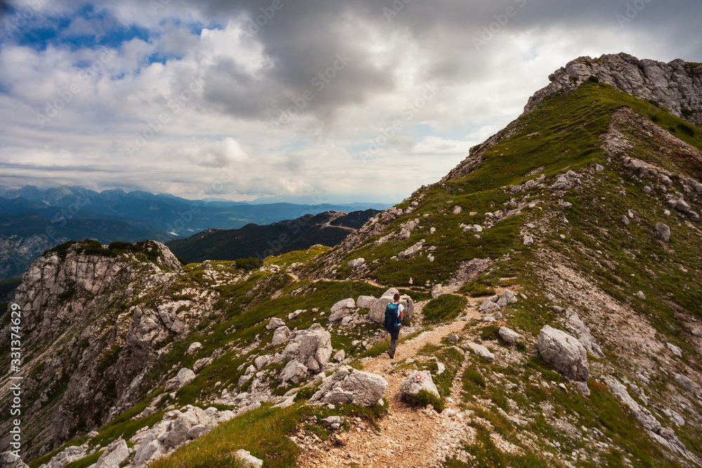 Young woman with backpack hiking along the path in the Vogel mountain, Slovenia Young woman with backpack hiking along the path in the Vogel mountain, Slovenia