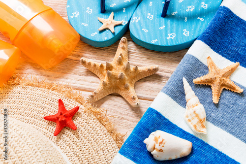 flip flops, straw hat, starfish, sunscreen bottle, body lotion spray on wooden background top view . flat lay summer beach sea accessories background, vaation concept photo