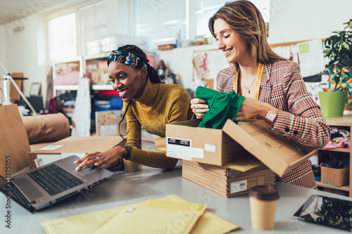 Sales Online. Working women at their store. They accepting new orders online and packing merchandise for customer. photo