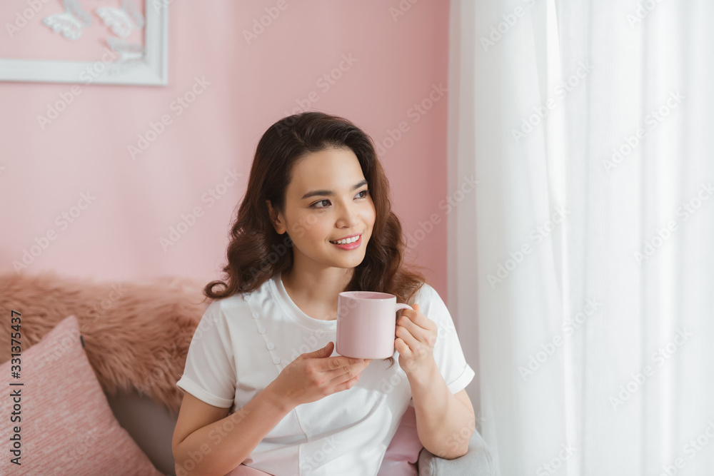 woman holding cup smiling into camera in living room woman holding cup smiling into camera in living room