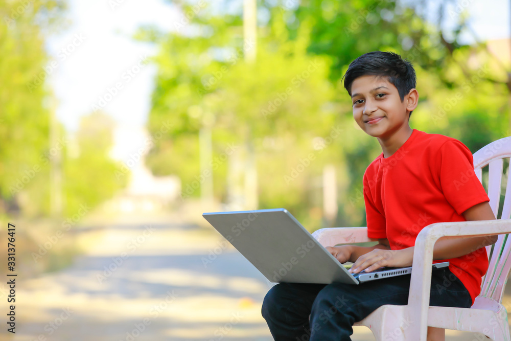 Cute little Indian/Asian boy studying or playing game with laptop computer Cute little Indian/Asian boy studying or playing game with laptop computer